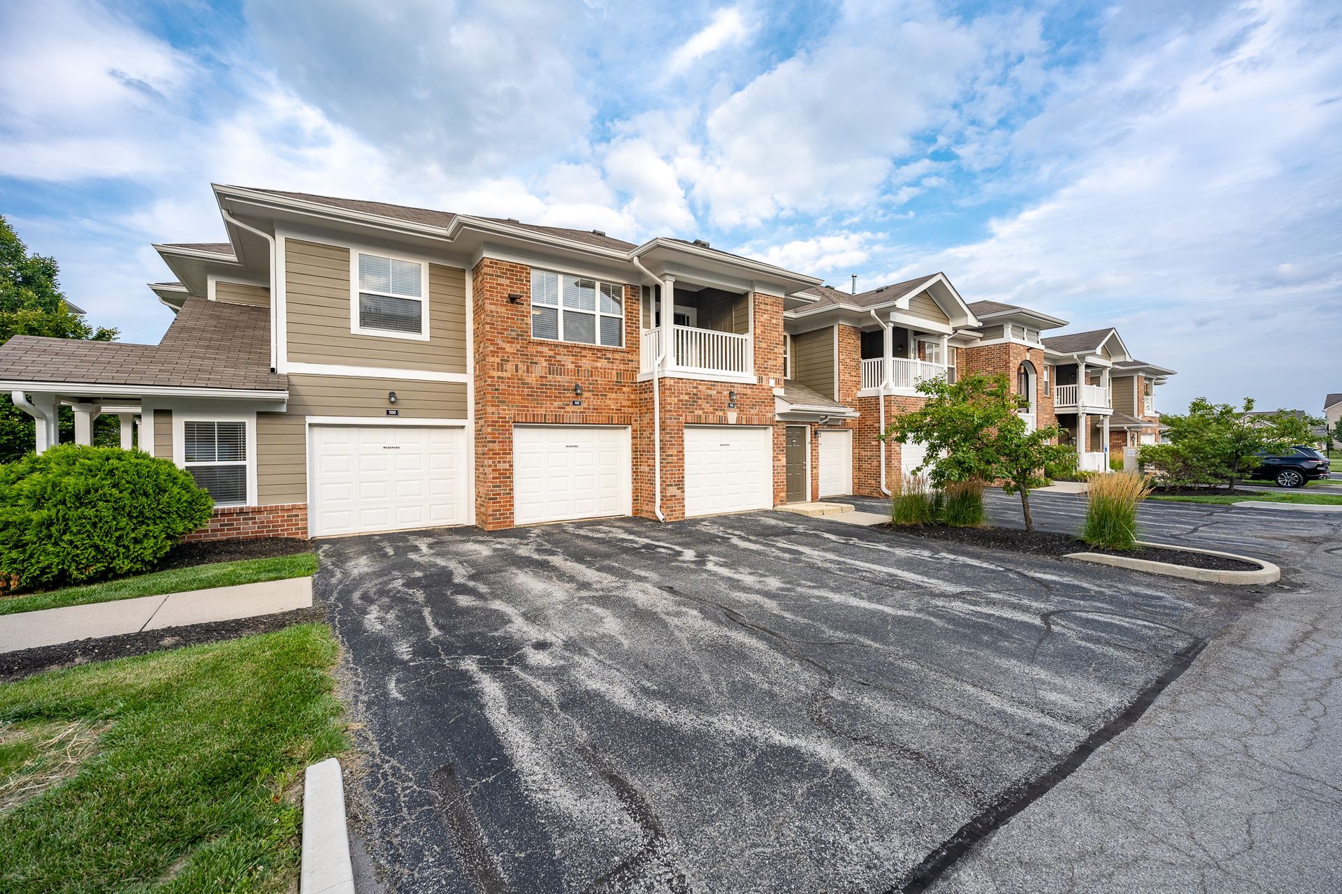 A row of apartment buildings with a parking lot in front of them at Maple Knoll Apartments