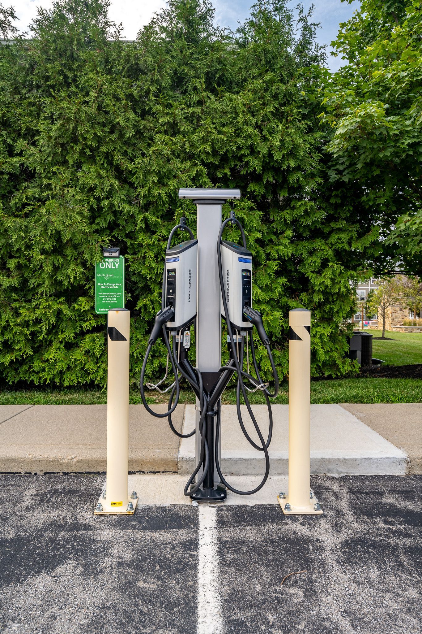 A charging station in a parking lot with trees in the background at Maple Knoll Apartments
