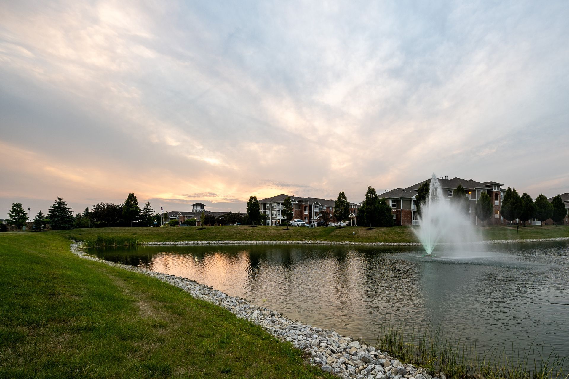A pond with a fountain in the middle of it at Maple Knoll Apartments