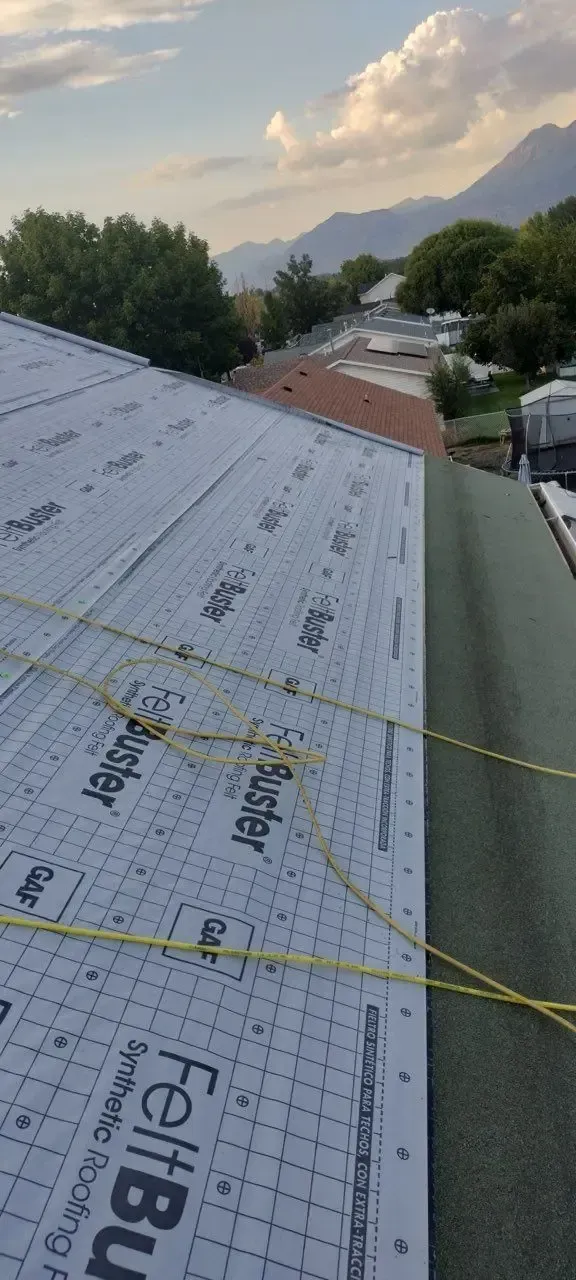 Rooftop with roofing felt and a mountain view. Yellow guide lines are strung across the surface.