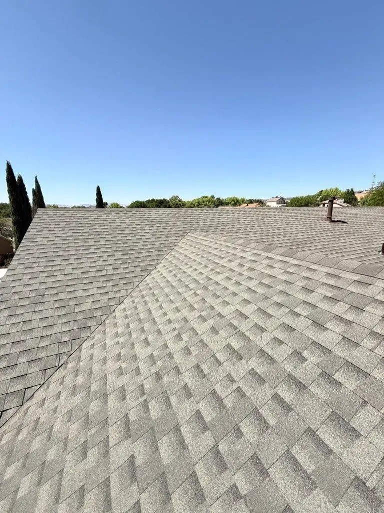 Gray shingled roof under a clear blue sky, viewed from above.