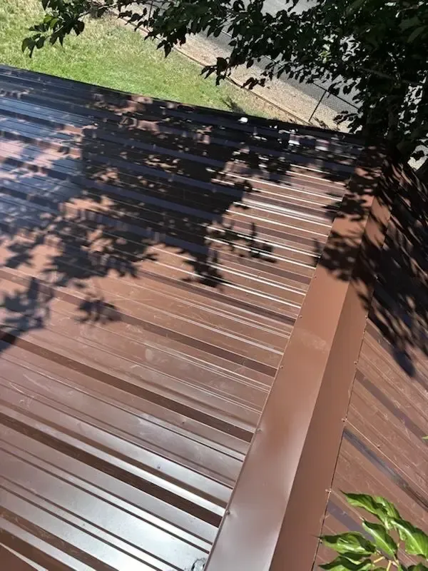 Brown metal roof with shadow of tree branches.