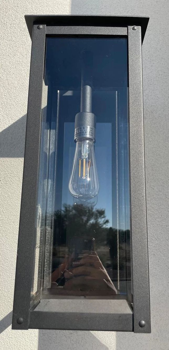 A lantern with a light inside of it is hanging on a wall.