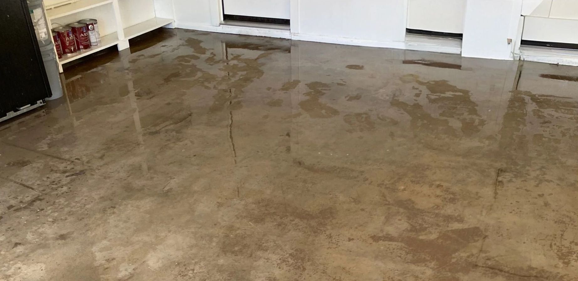 A kitchen with a brown concrete floor and white cabinets.