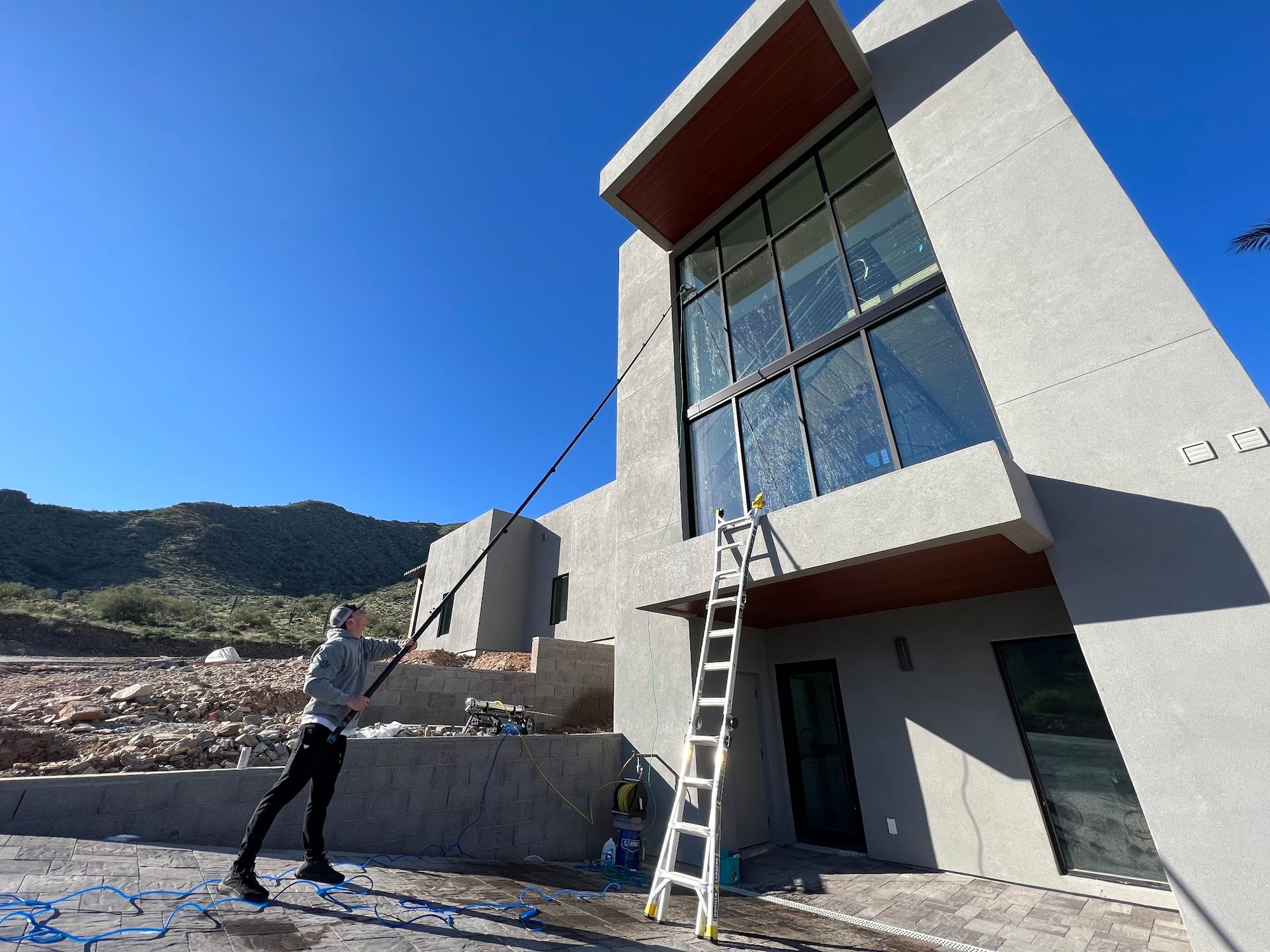 A man is cleaning the windows of a house with a ladder.
