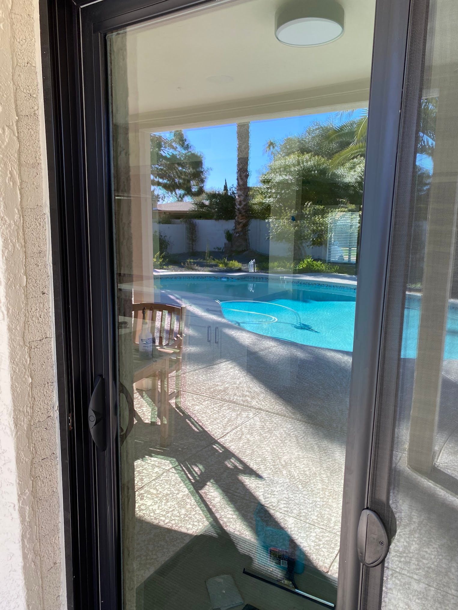 A sliding glass door with a view of a swimming pool.