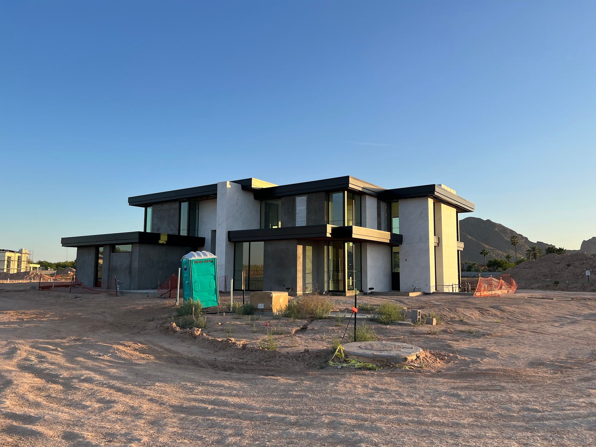 A large house is being built in the middle of a dirt field.