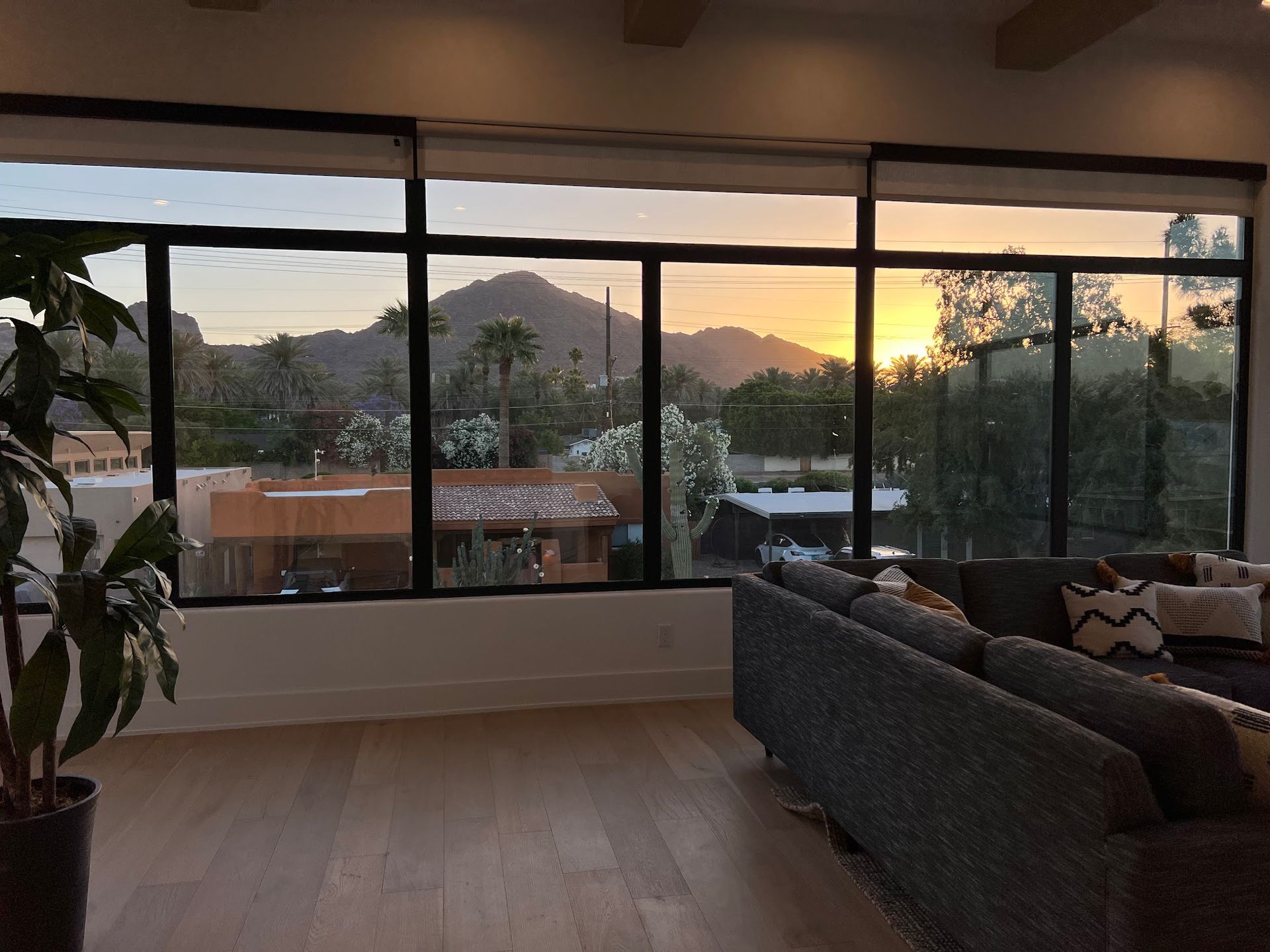 A living room with a couch and a view of the sunset through the windows.