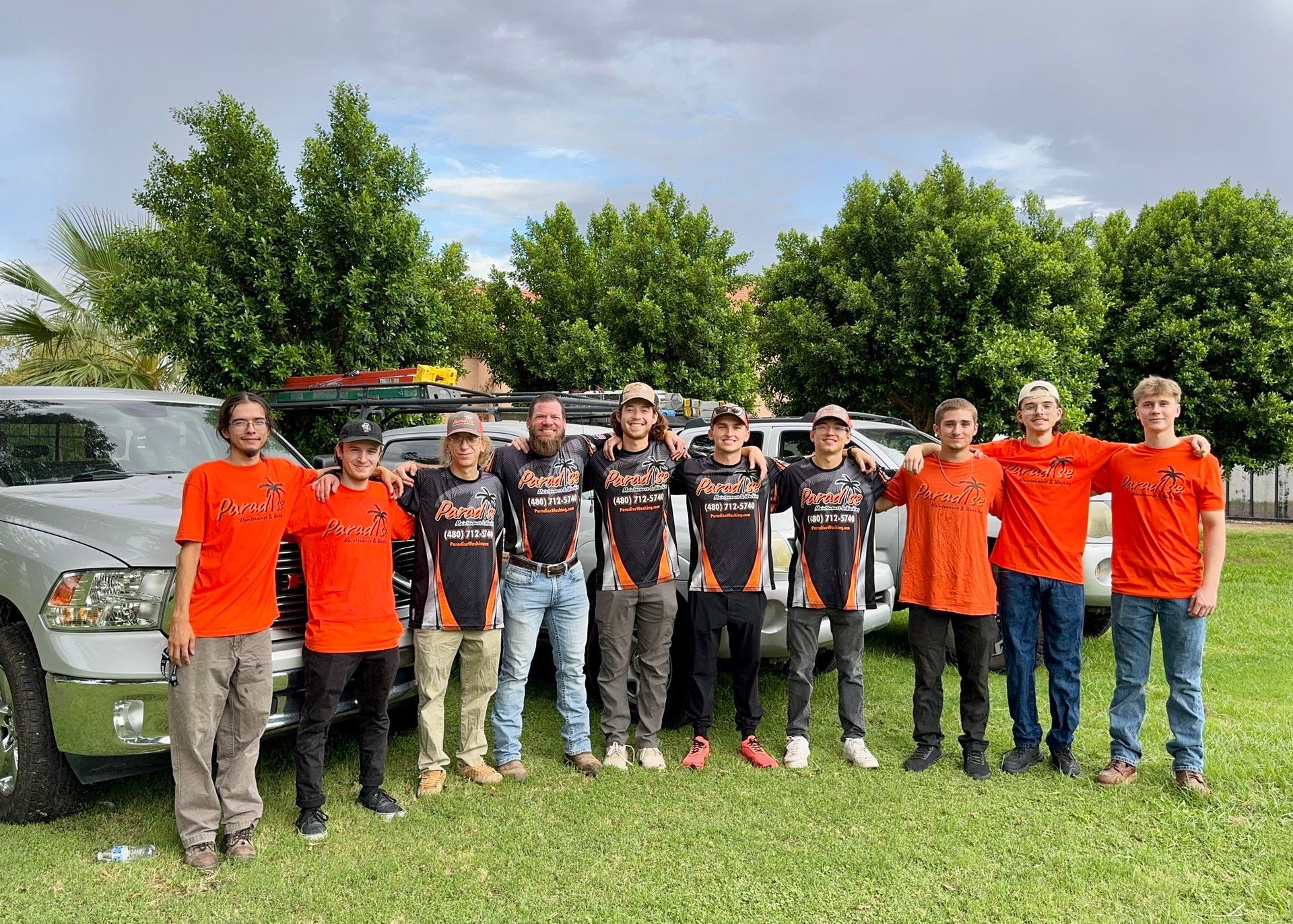 A group of men are posing for a picture in front of their trucks.