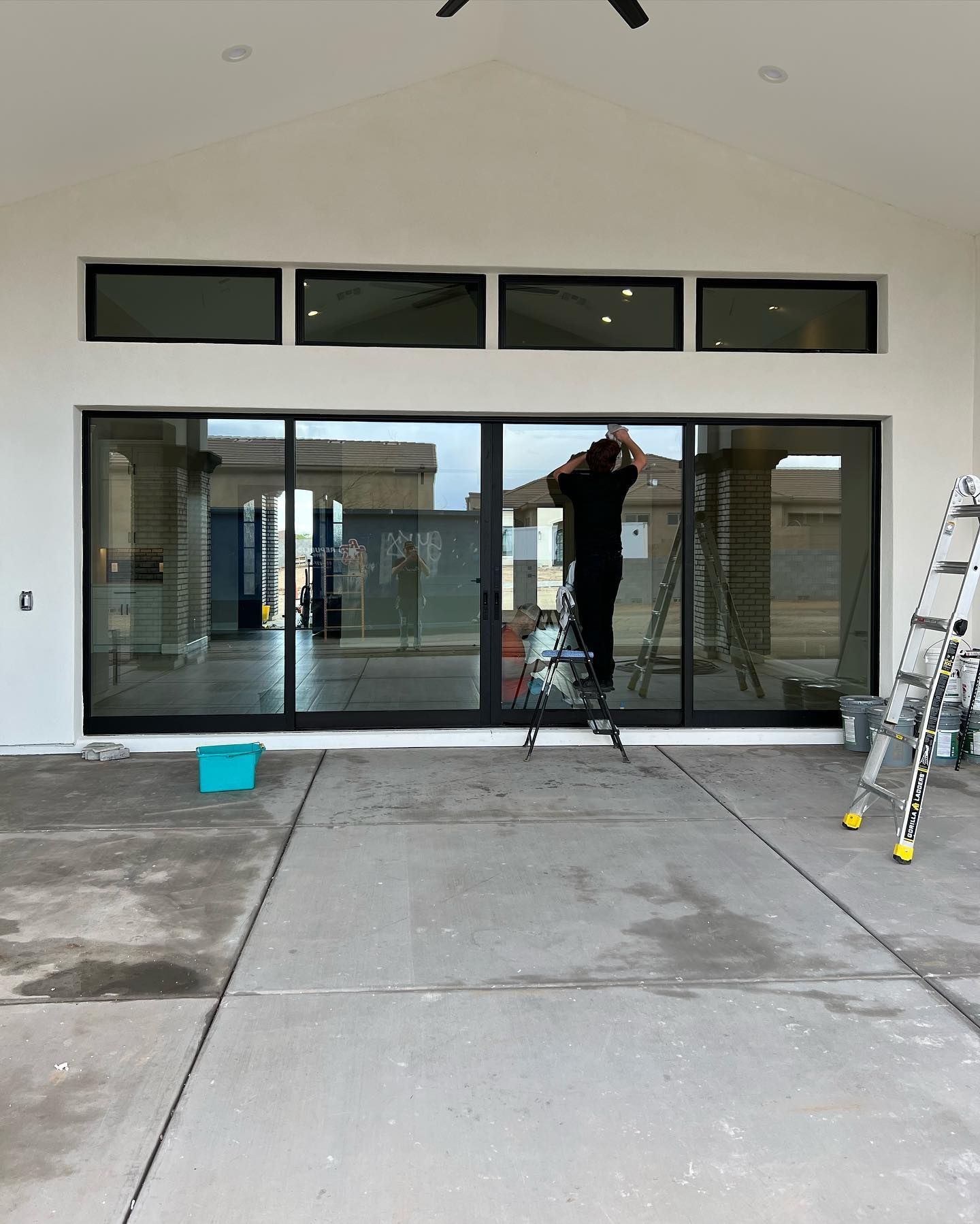 A man is standing on a ladder in front of a sliding glass door.