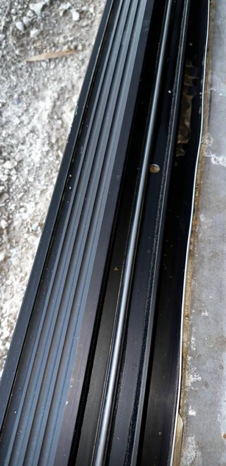 A window with blinds on it and a reflection of a house in the window.