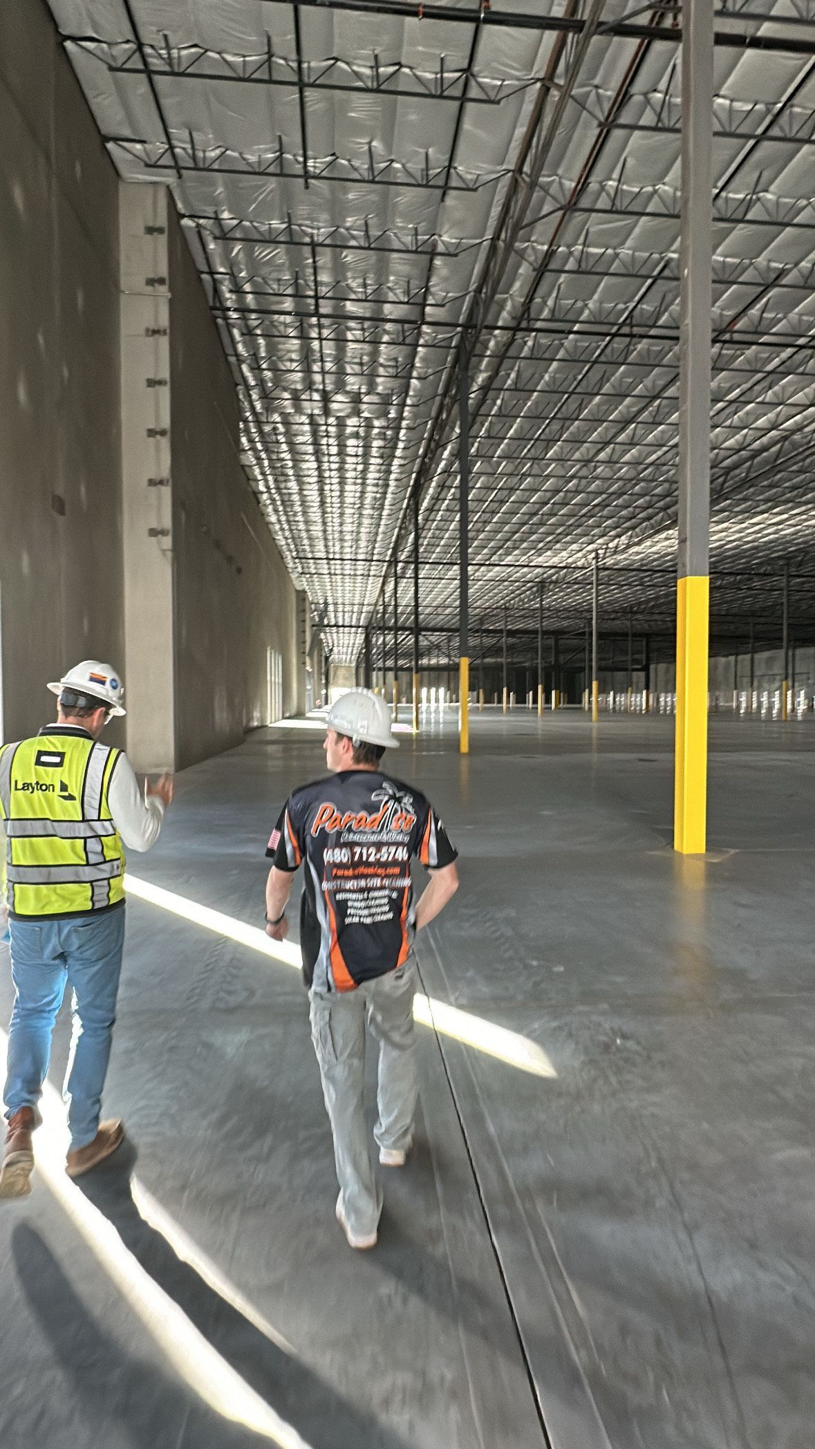 Two men are walking through an empty warehouse.
