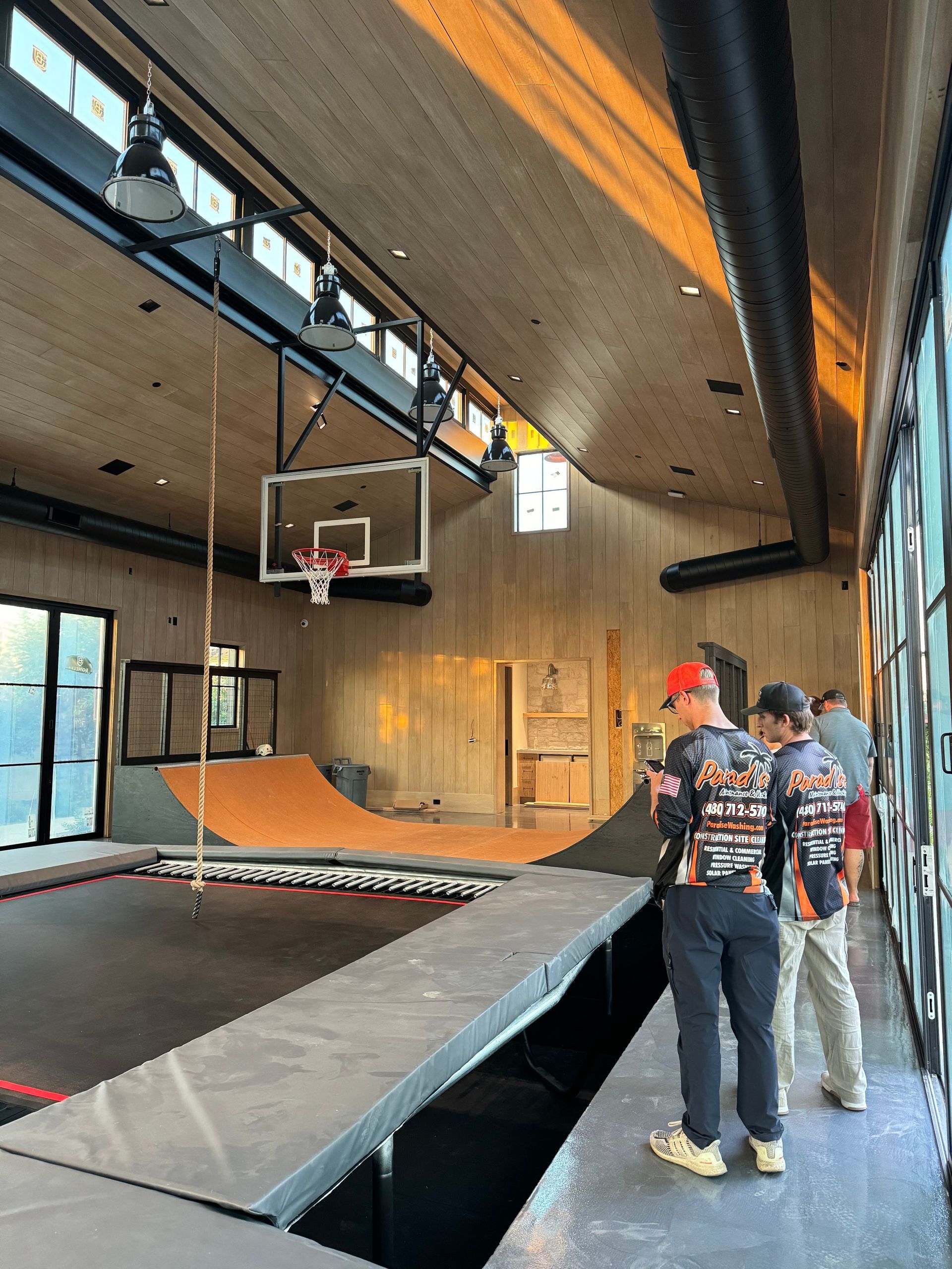 A group of men are standing in a room with a trampoline and a basketball hoop.