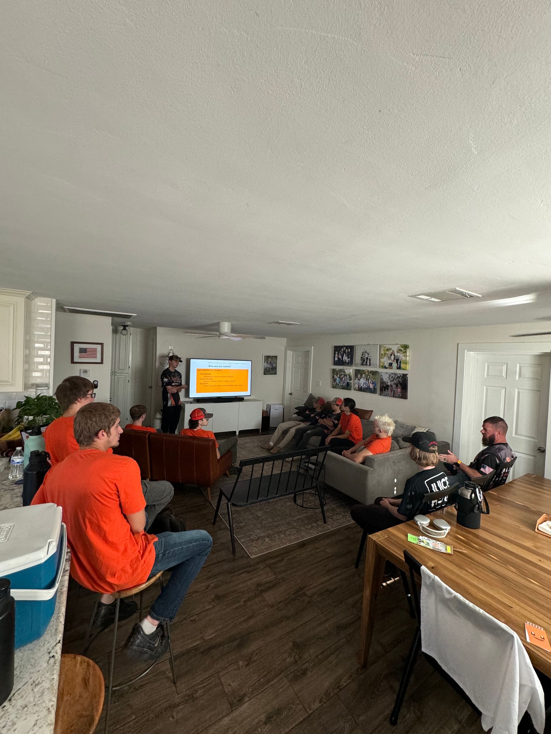 A group of people are sitting in a living room watching a game on a television.