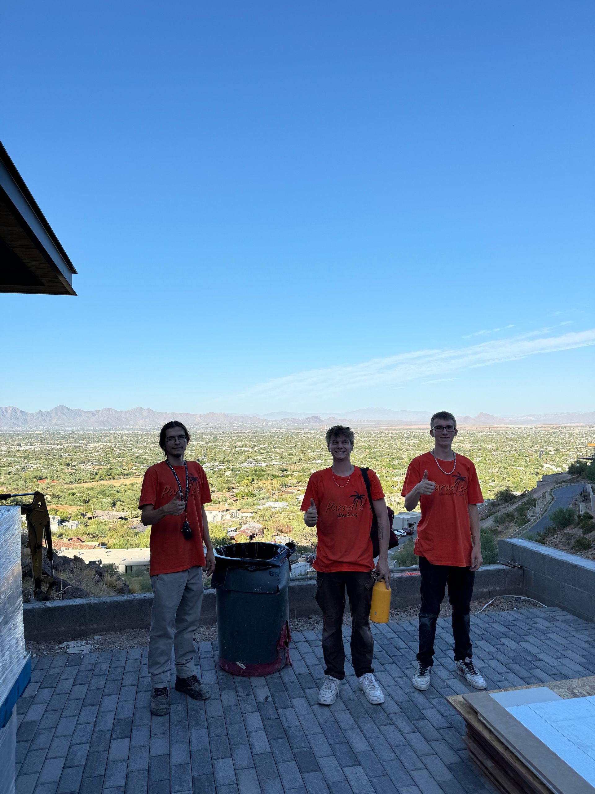 Three men are standing on a brick patio with a view of a city.