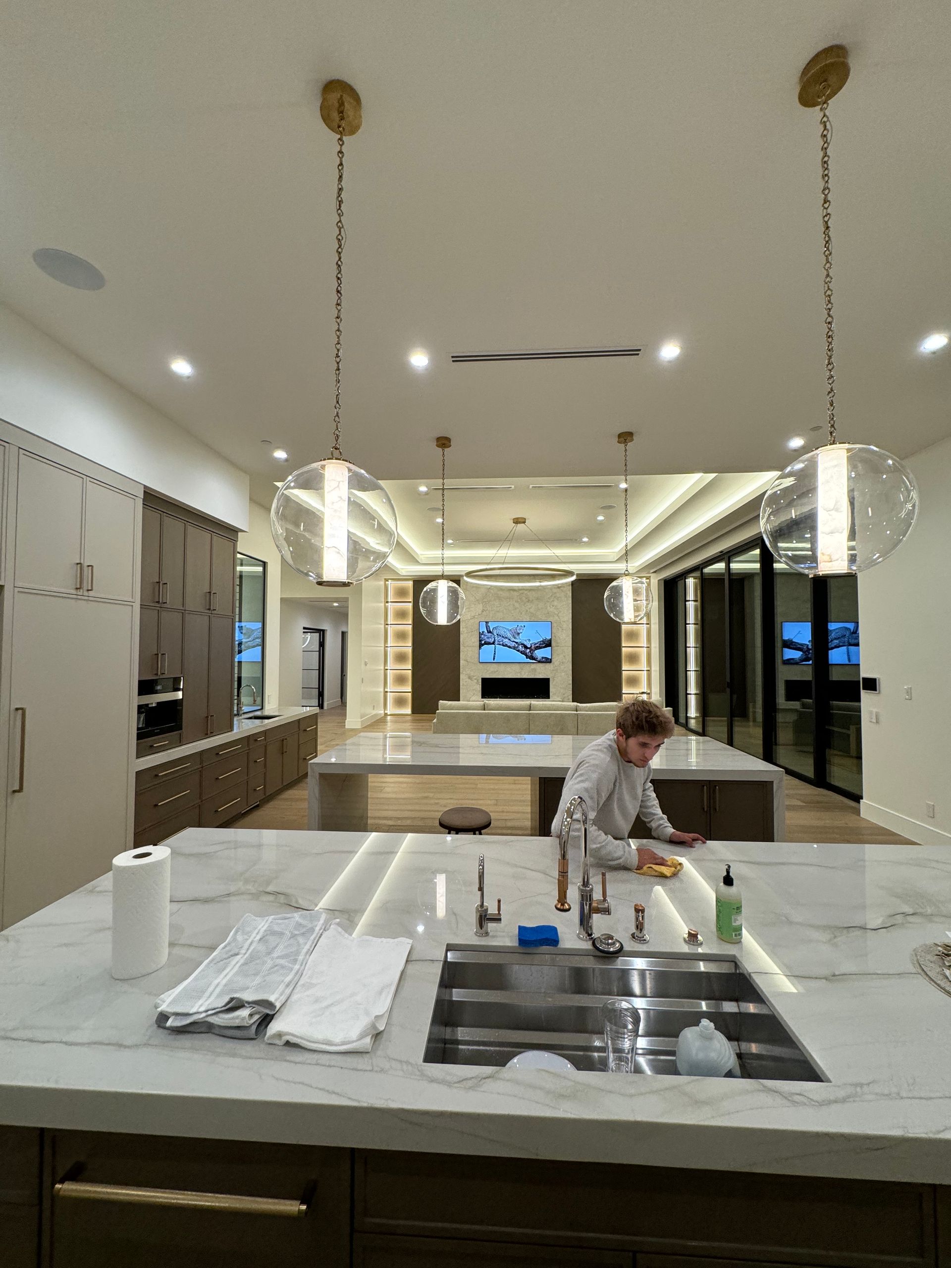 A man is cleaning a kitchen counter with a sink.