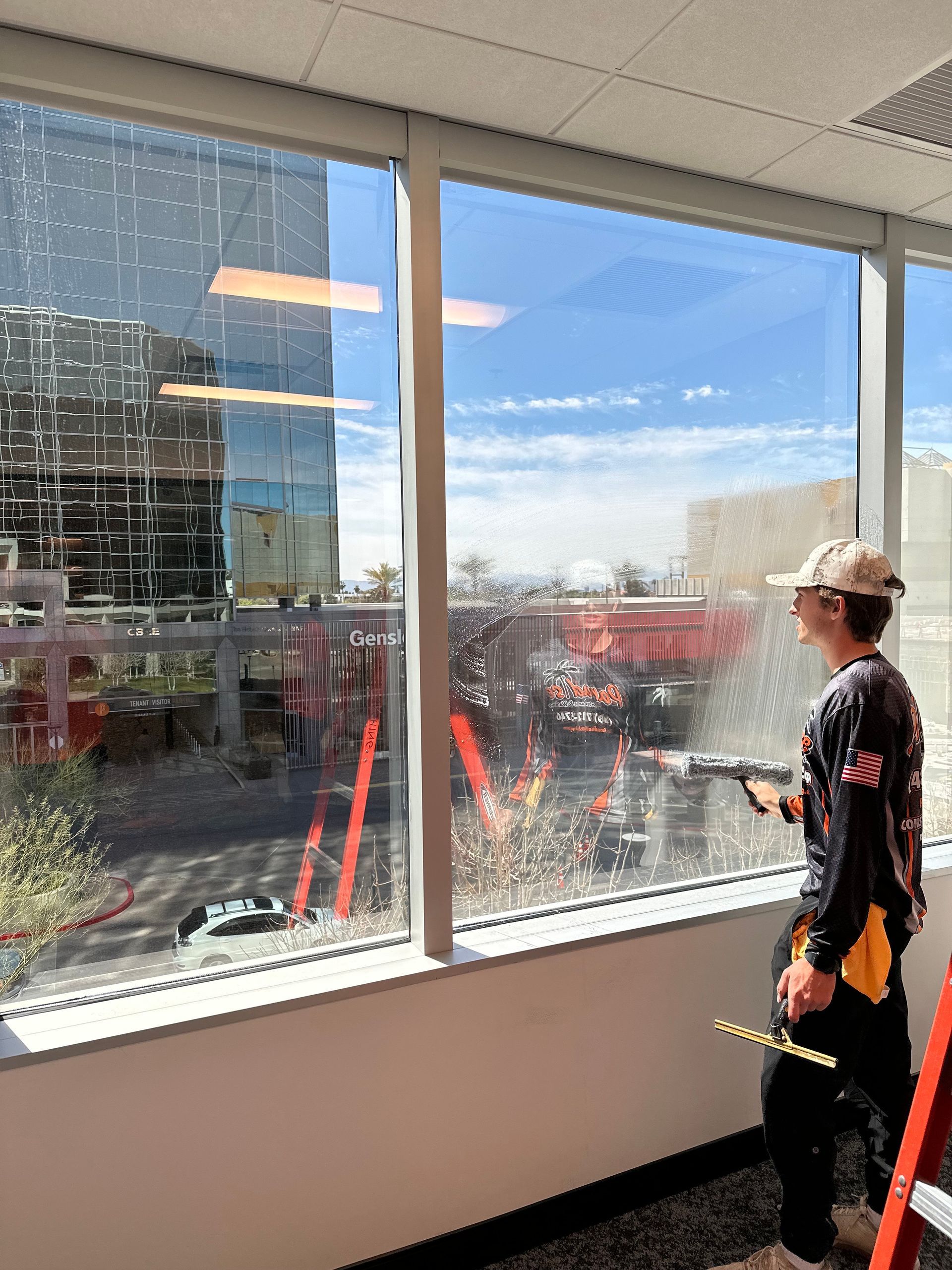A man is standing in front of a large window cleaning it.