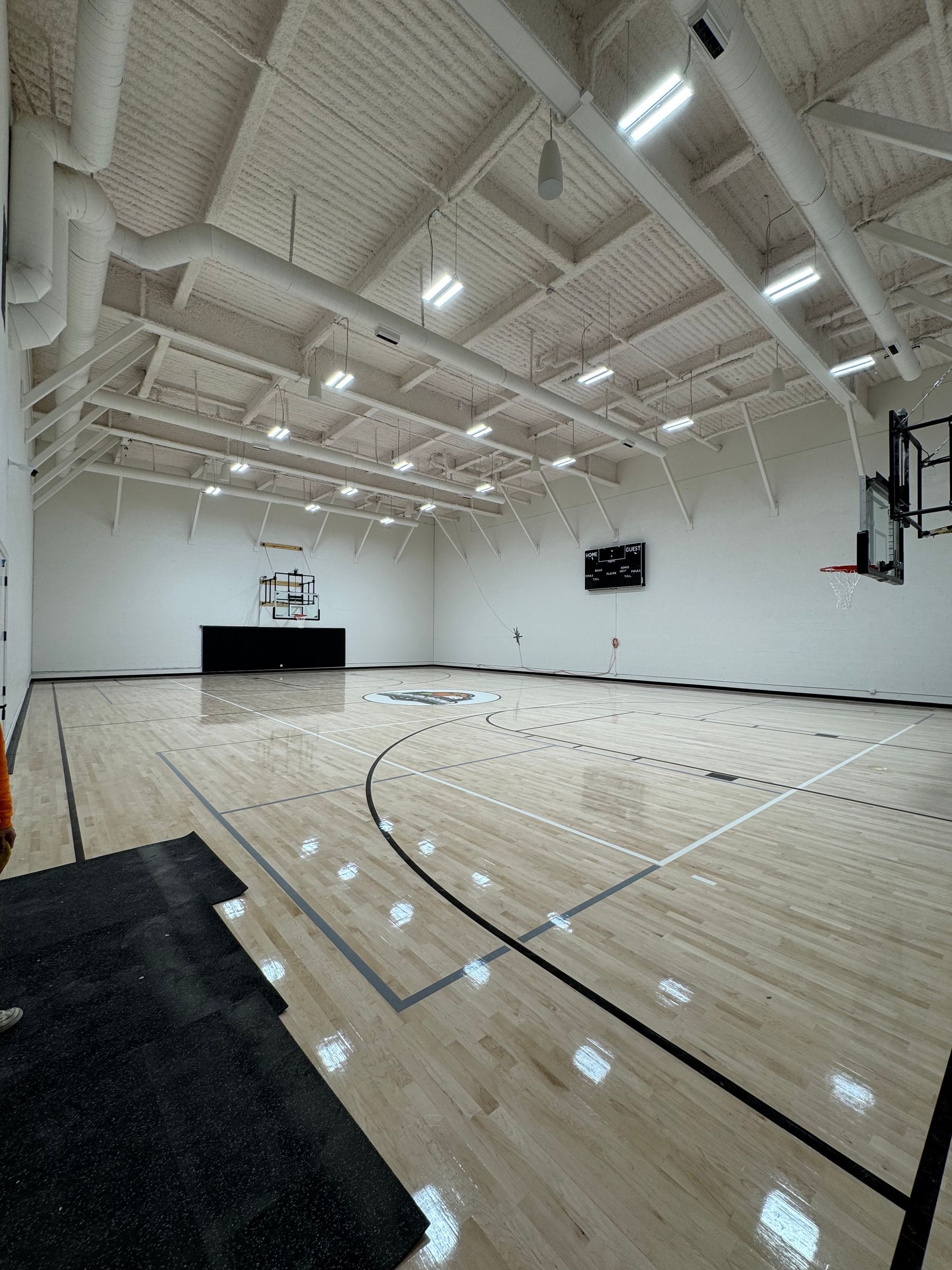 A large indoor basketball court with a wooden floor and a basketball hoop.
