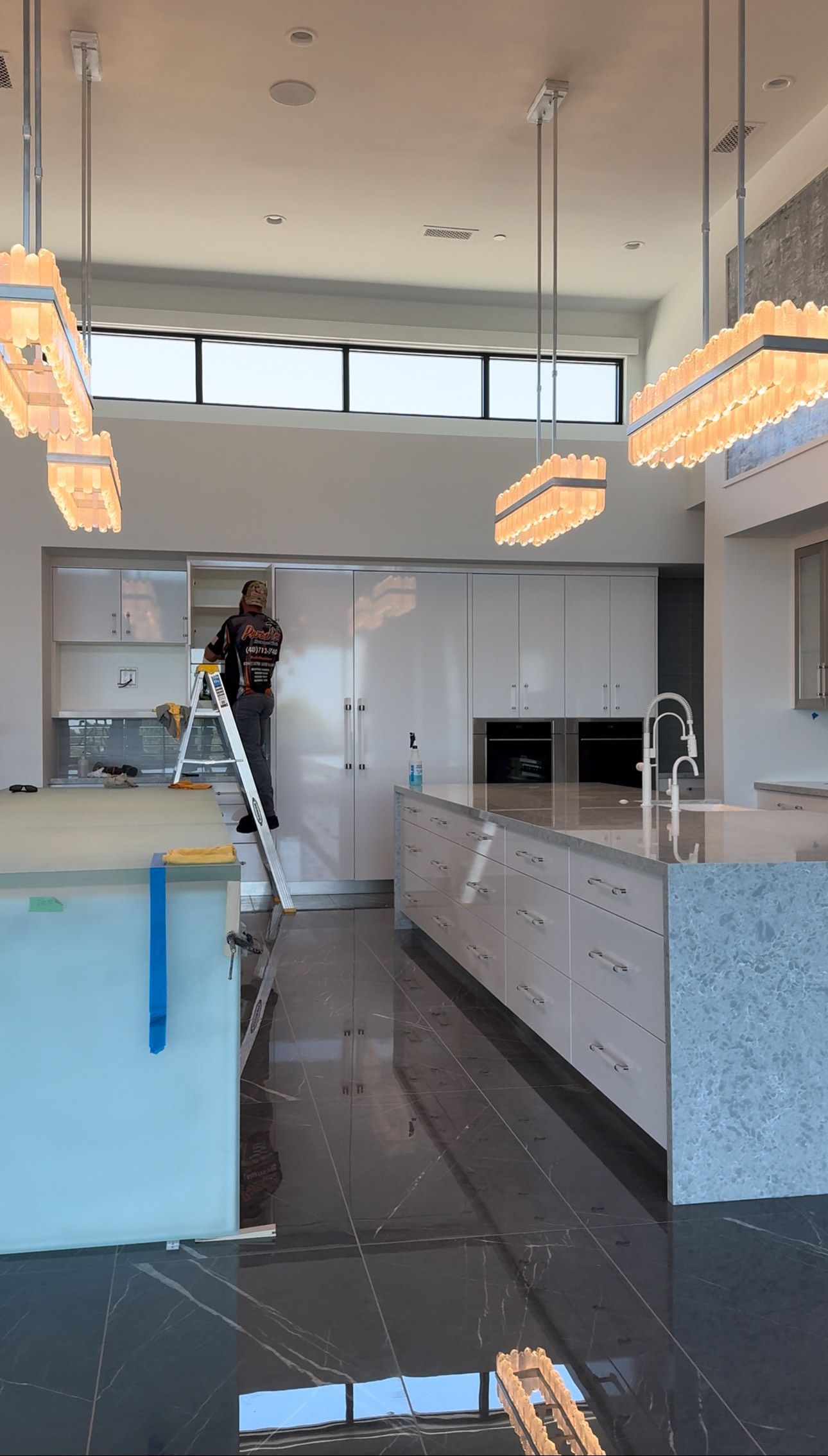 A man is standing on a ladder in a kitchen.