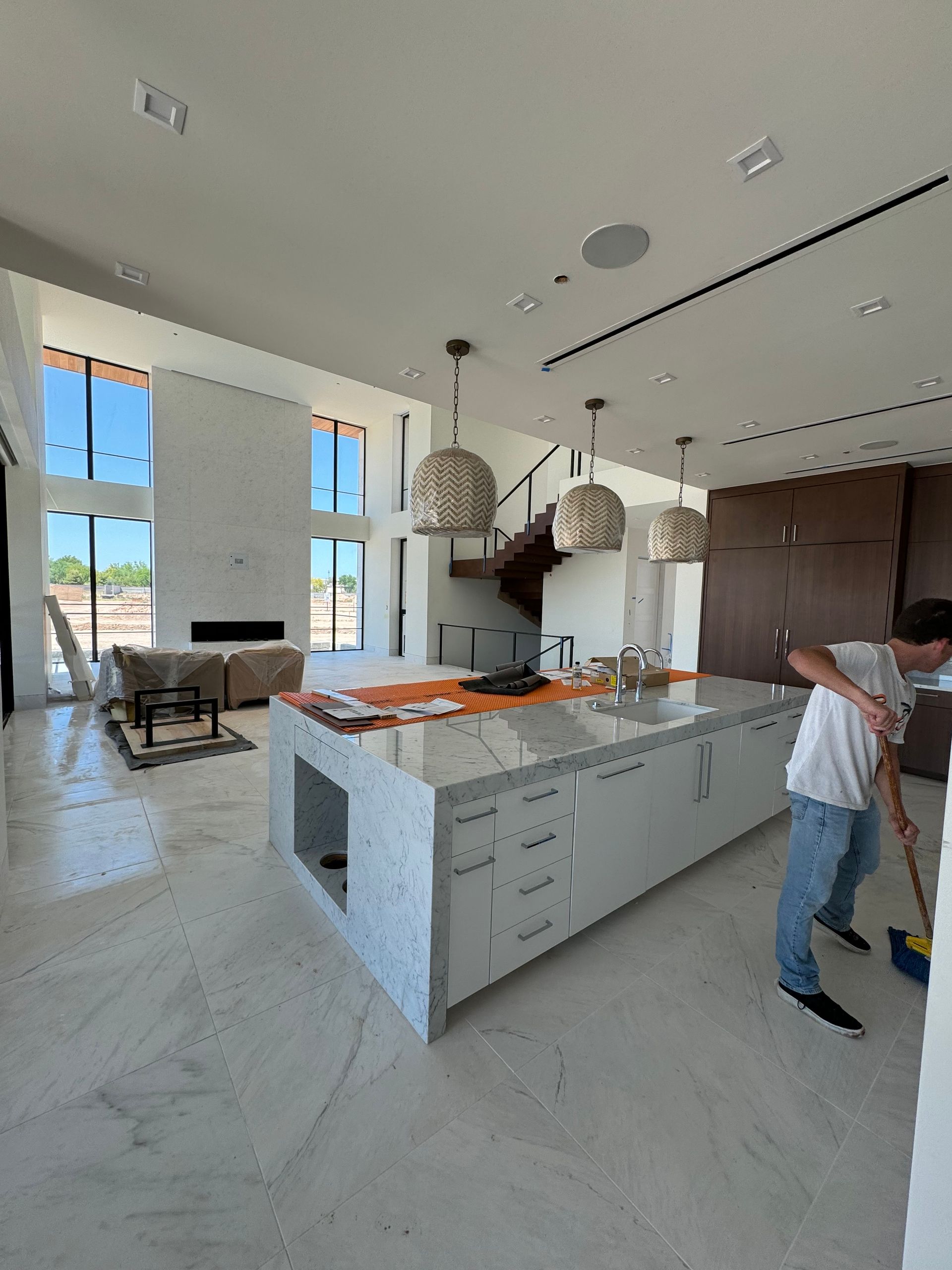 A man is sweeping the floor in a large kitchen.