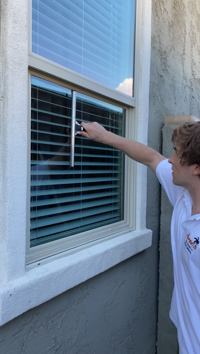 A man is cleaning a window with a squeegee.