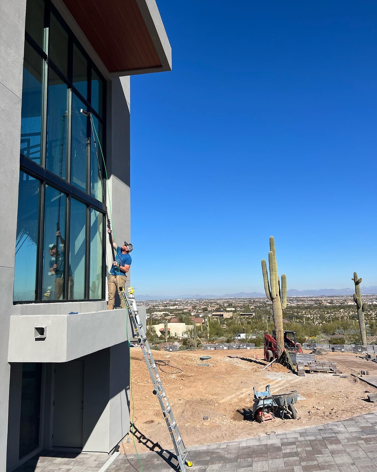 A man is standing on a balcony of a building cleaning windows.