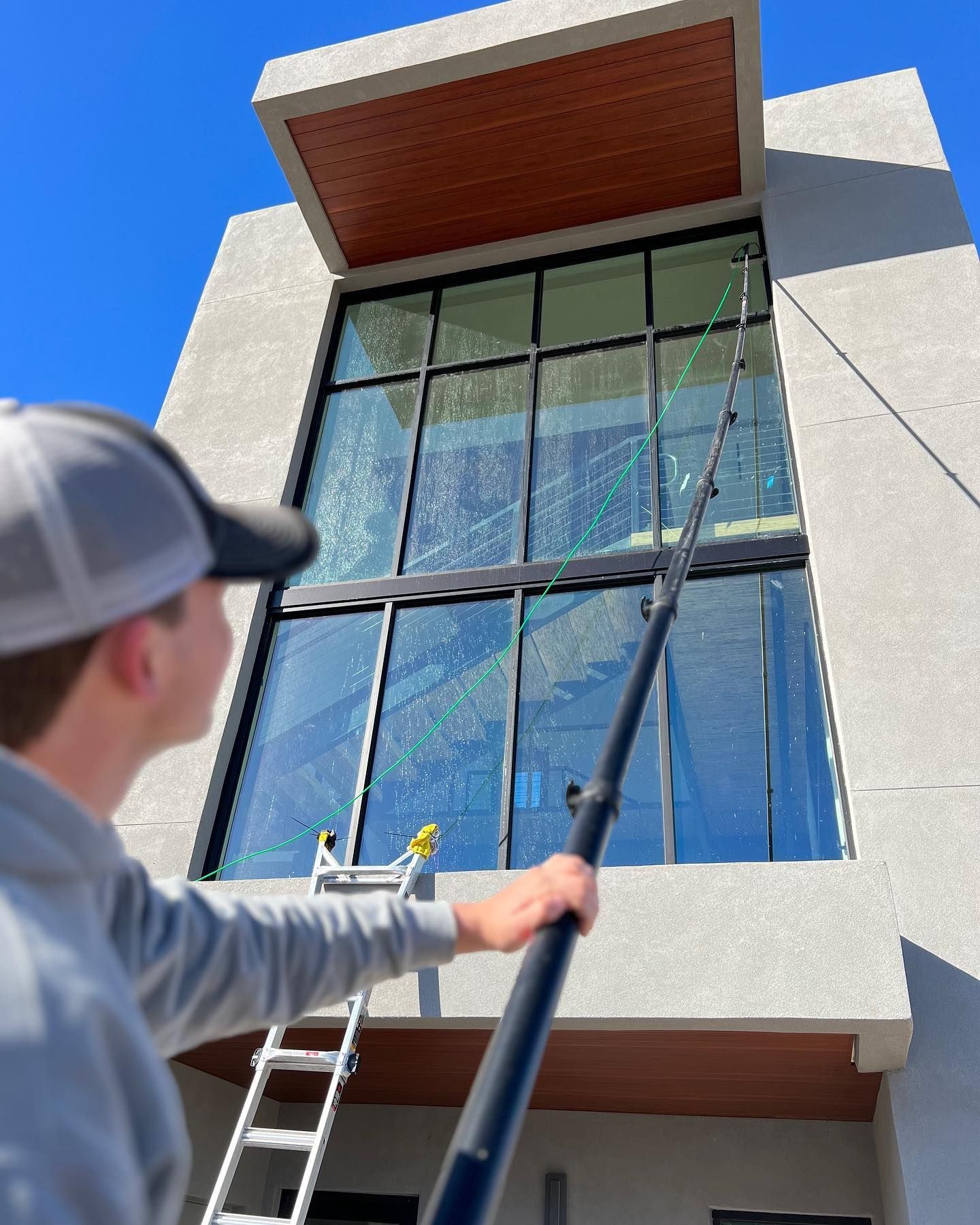 A man is cleaning the windows of a building with a pole.