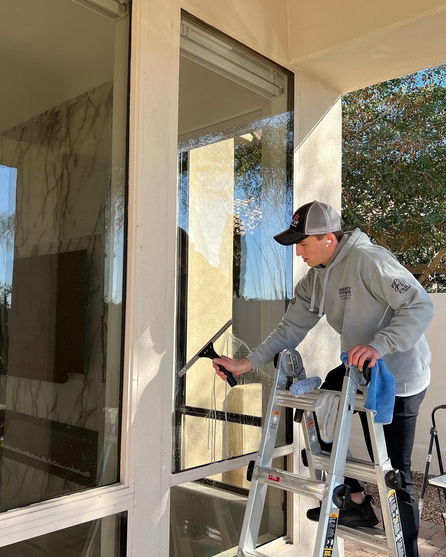 A man is standing on a ladder cleaning a window.