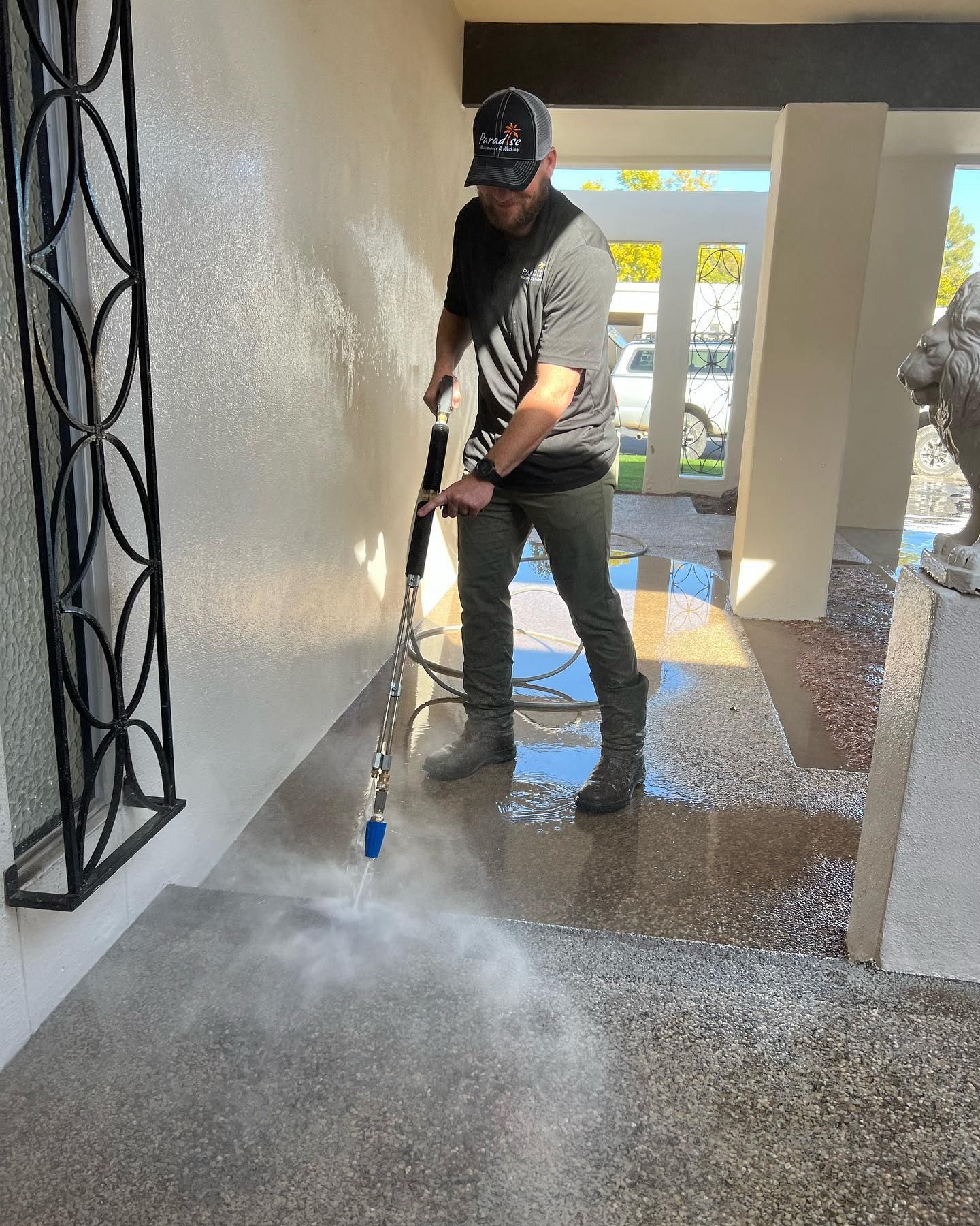 A man is cleaning the sidewalk with a pressure washer.