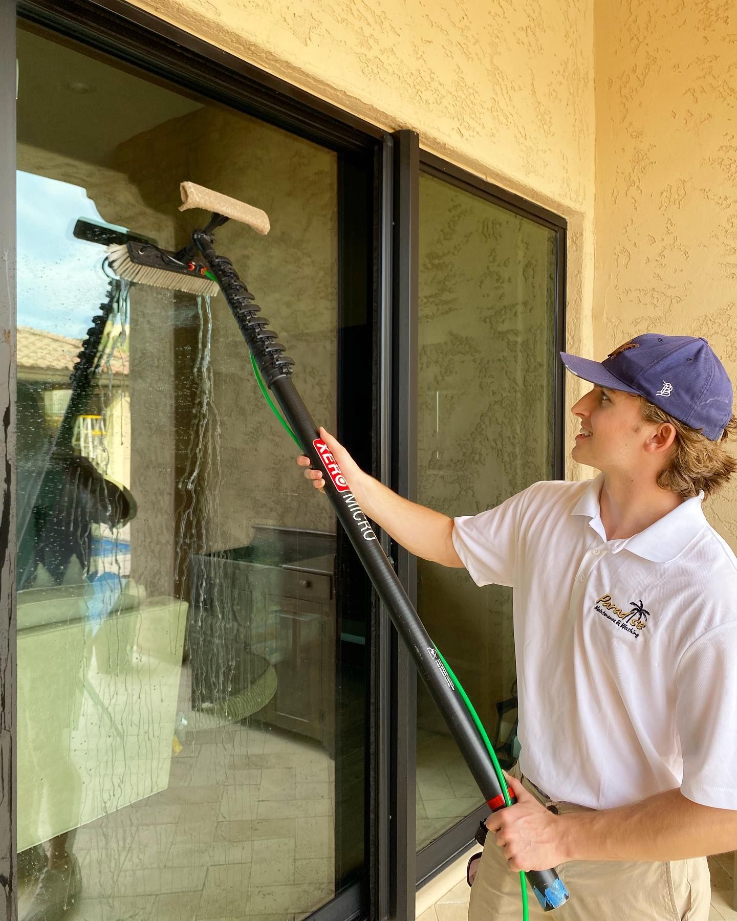A man is cleaning a window with a long pole.