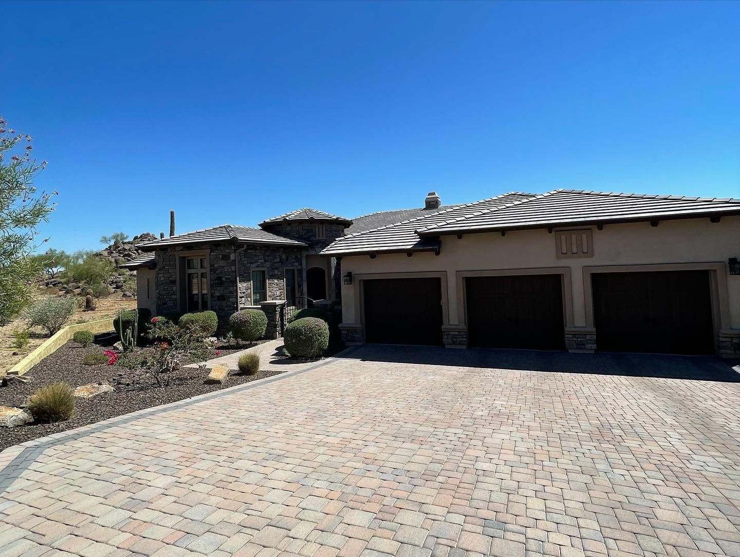 A large house with three garages and a brick driveway.