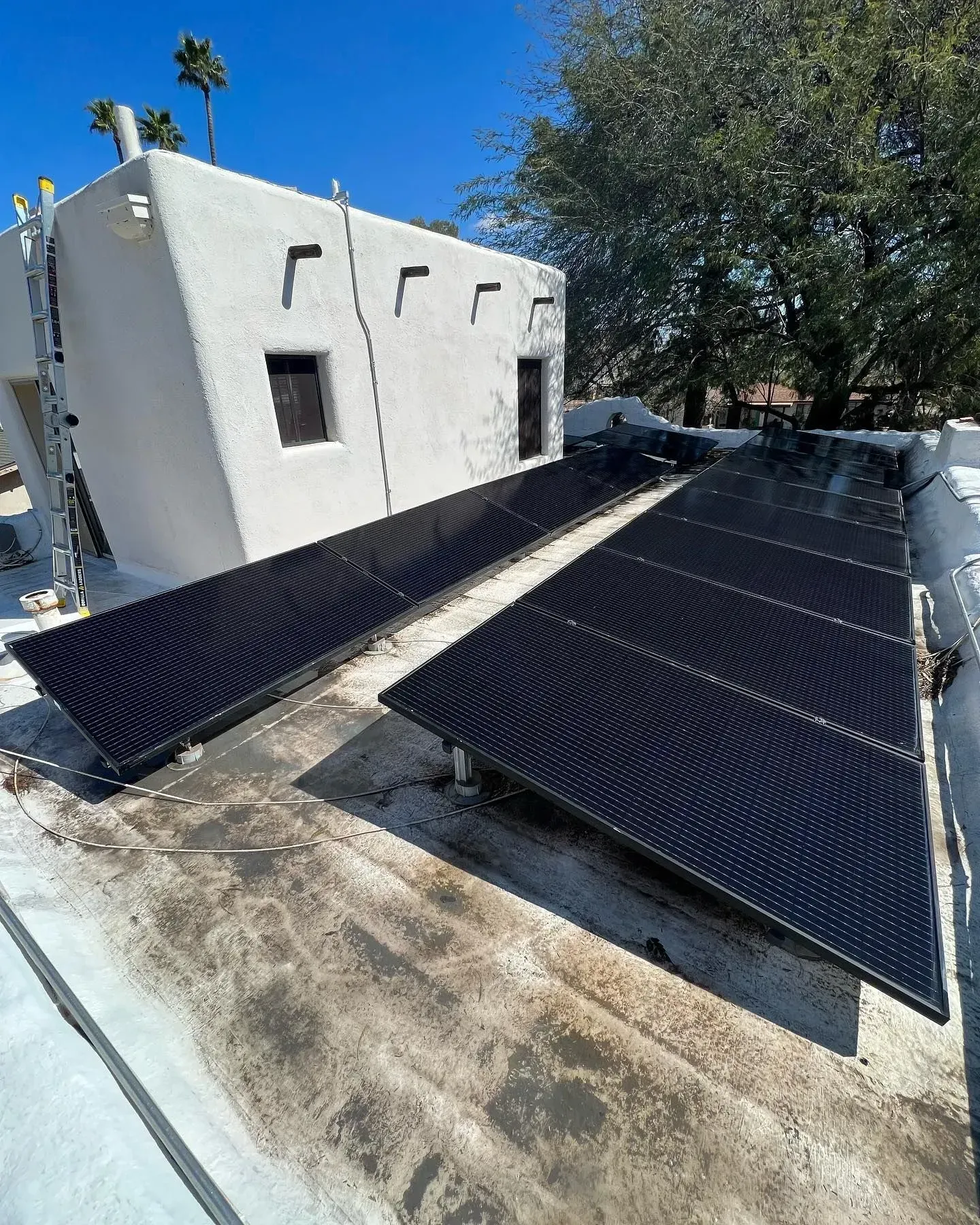 Solar panels on a white stucco building roof, angled toward the sun.