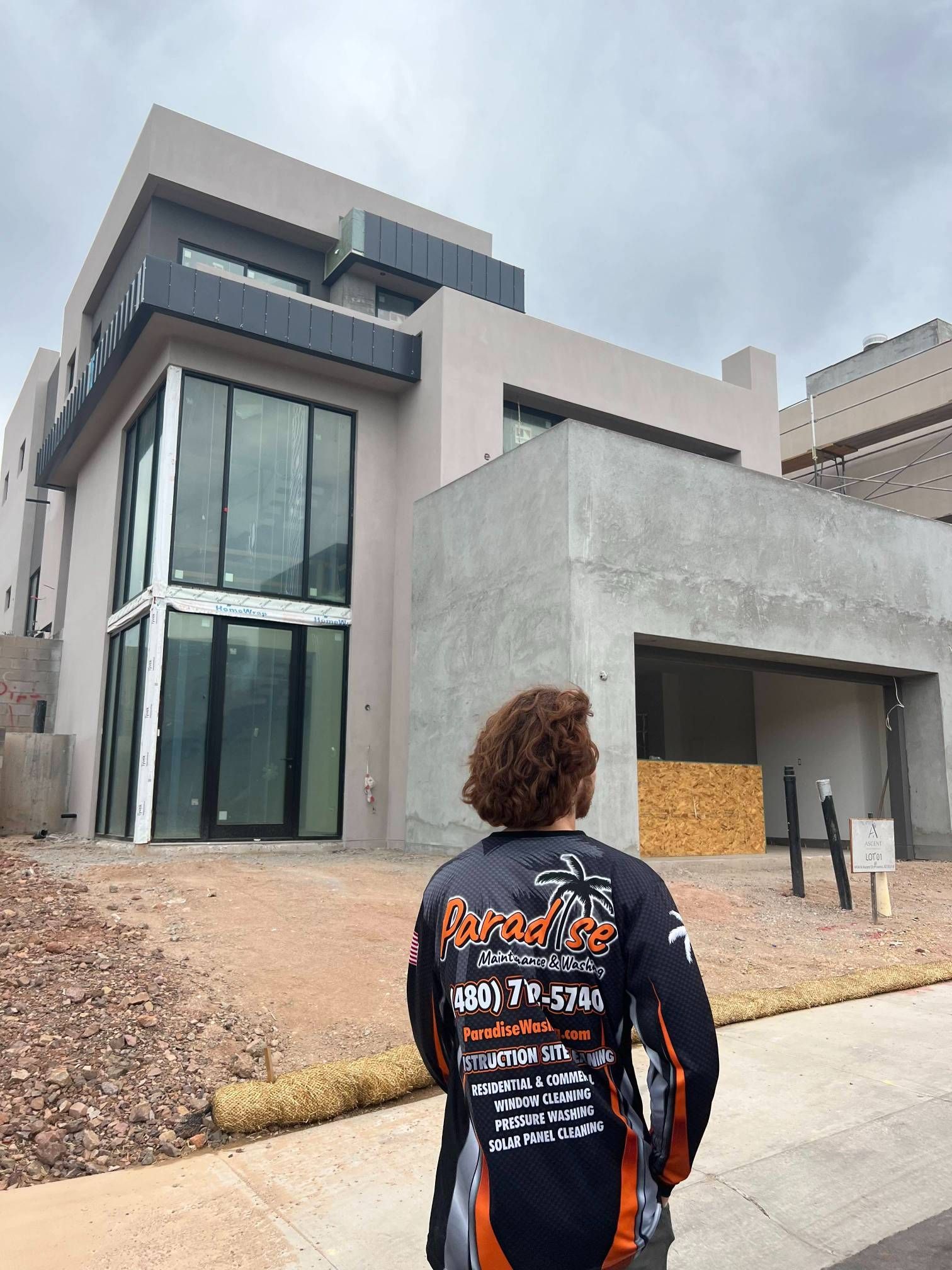Person in uniform looks at a modern, unfinished house with large windows.