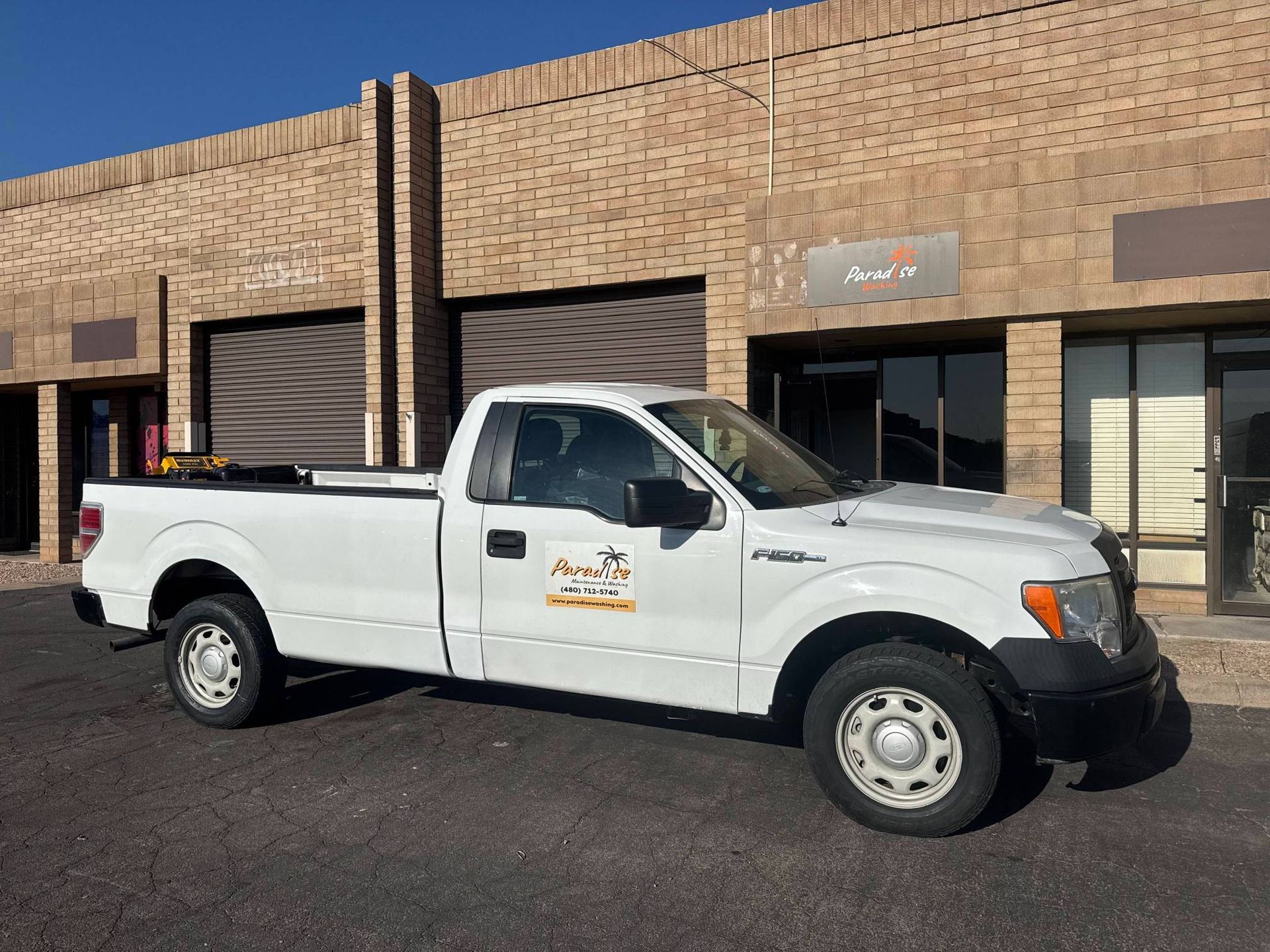 White Ford pickup truck parked in front of a brick building.
