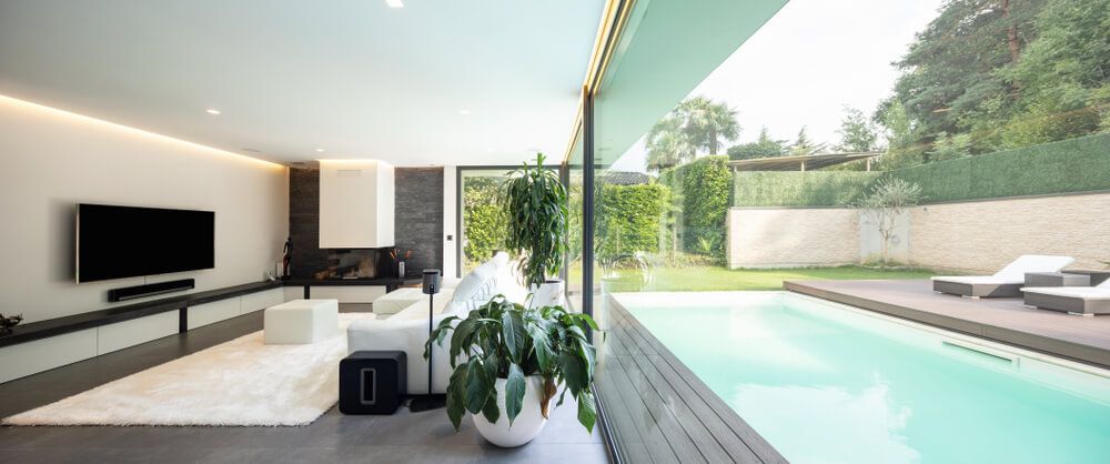 Modern Living Room With White Furniture and Large Glass Wall Overlooking a Backyard Pool and Garden — Complete Audio in Hervey Bay, QLD