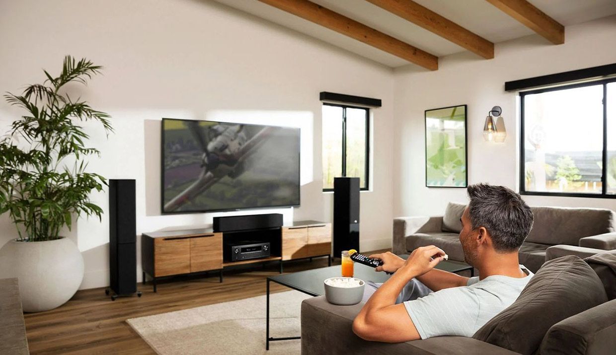 A Man is Sitting on a Couch in a Living Room Playing a Video Game — Complete Audio in Noosa, QLD