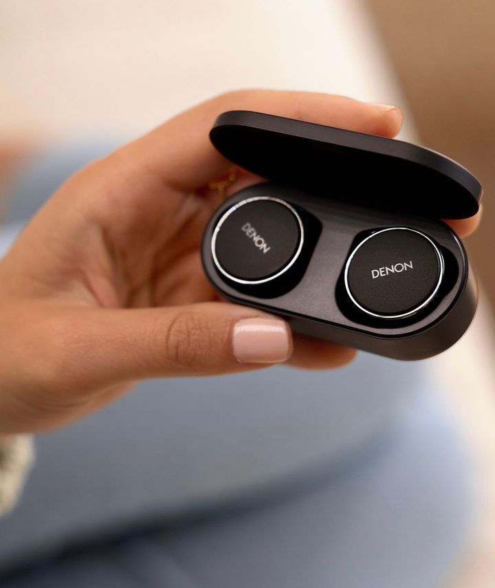 A Person is Holding a Pair of Denon Earbuds in Their Hand — Complete Audio in Maroochydore, QLD