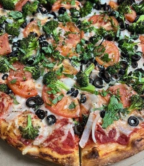 Vegan veggie pizza with tomatoes, broccoli, and black olives