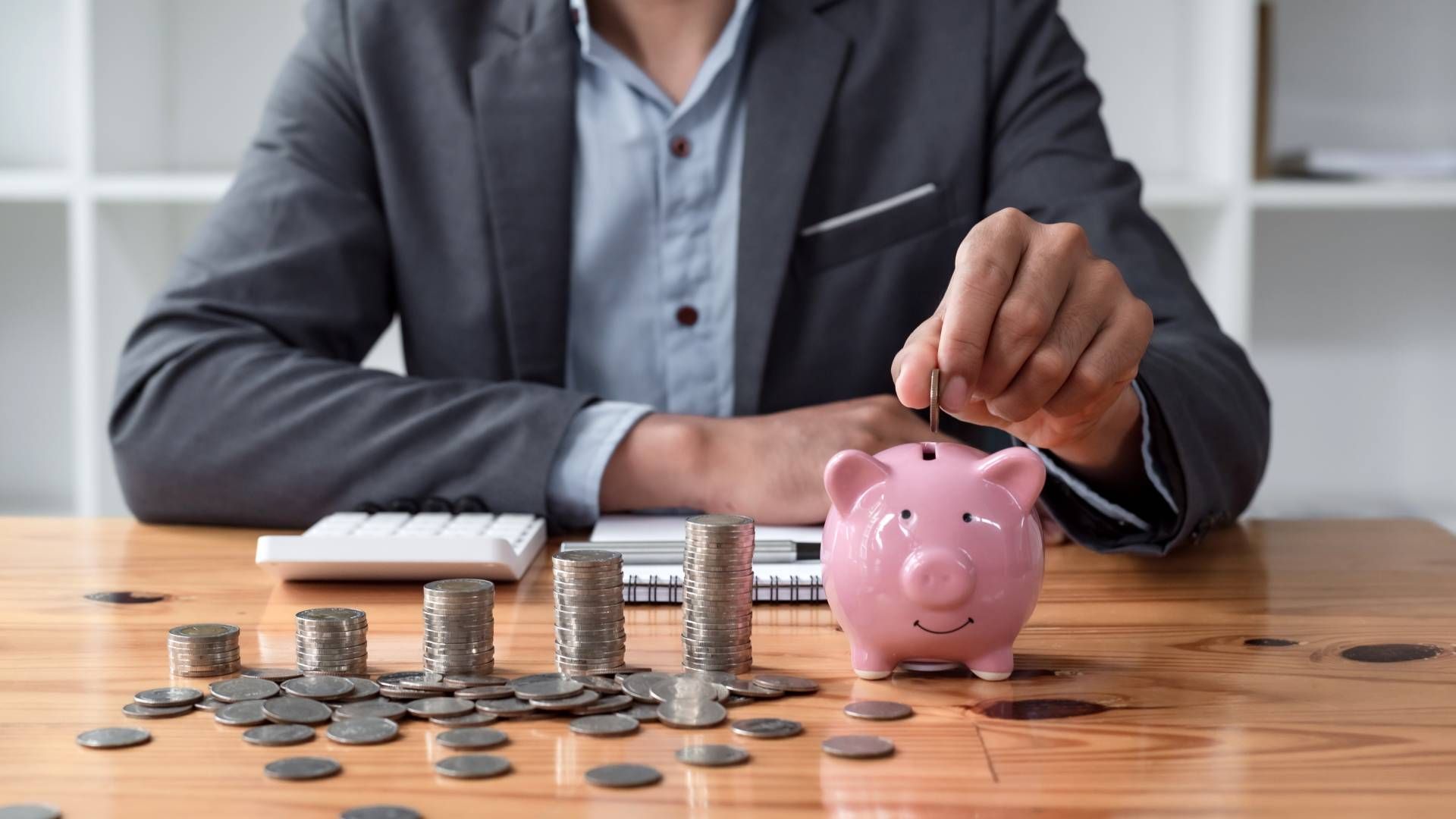 A man is putting coins into a piggy bank.