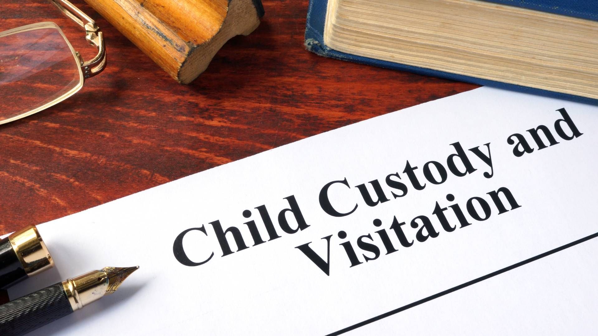 A child custody and visitation form with a pen and glasses