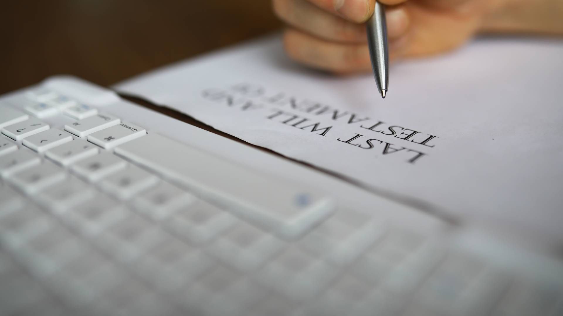 A person is writing a last will and testament on a piece of paper.
