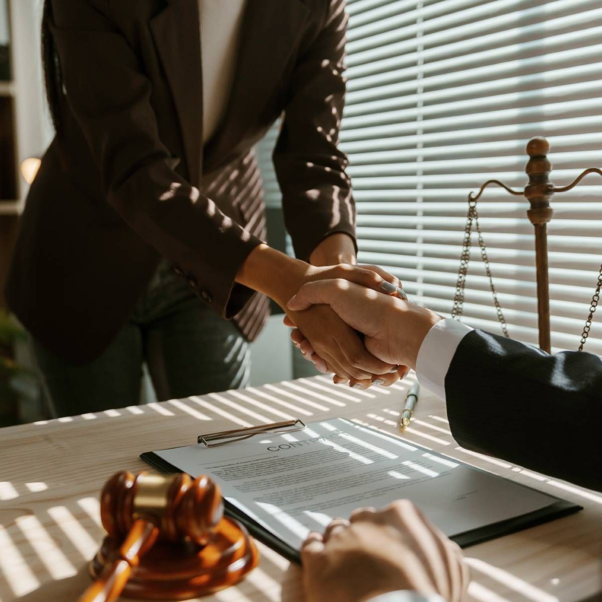 A man and a woman are shaking hands in front of a judge 's gavel.