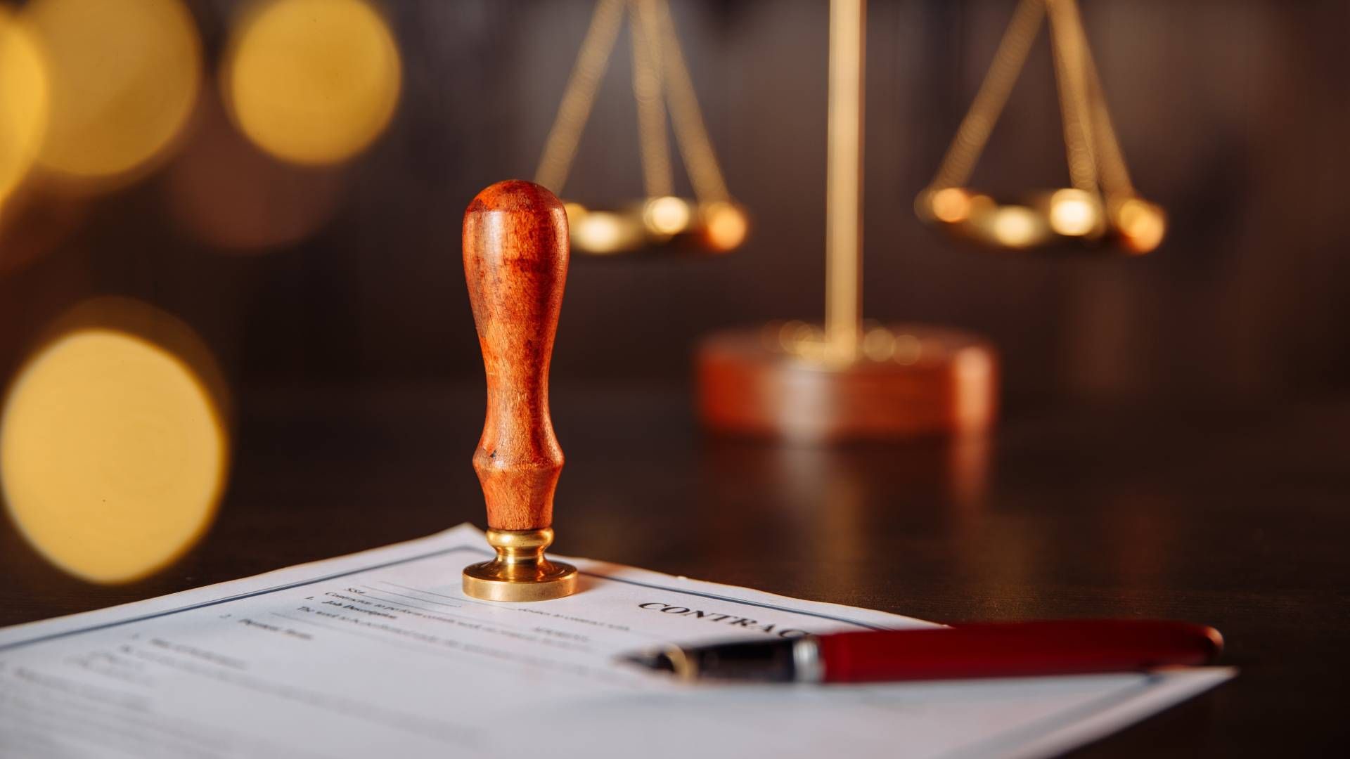 A notary stamp is sitting on top of a piece of paper next to a pen and scales of justice.