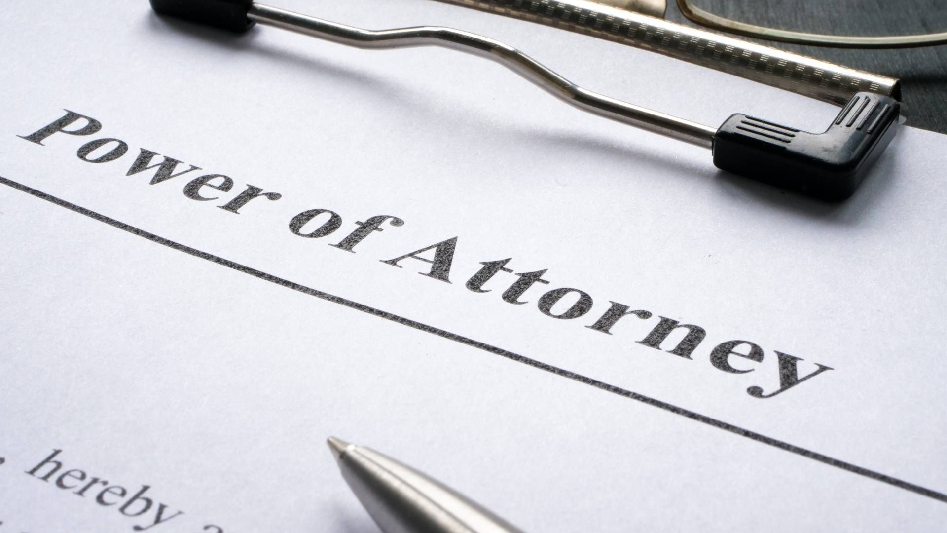 A power of attorney is on a clipboard next to a pen