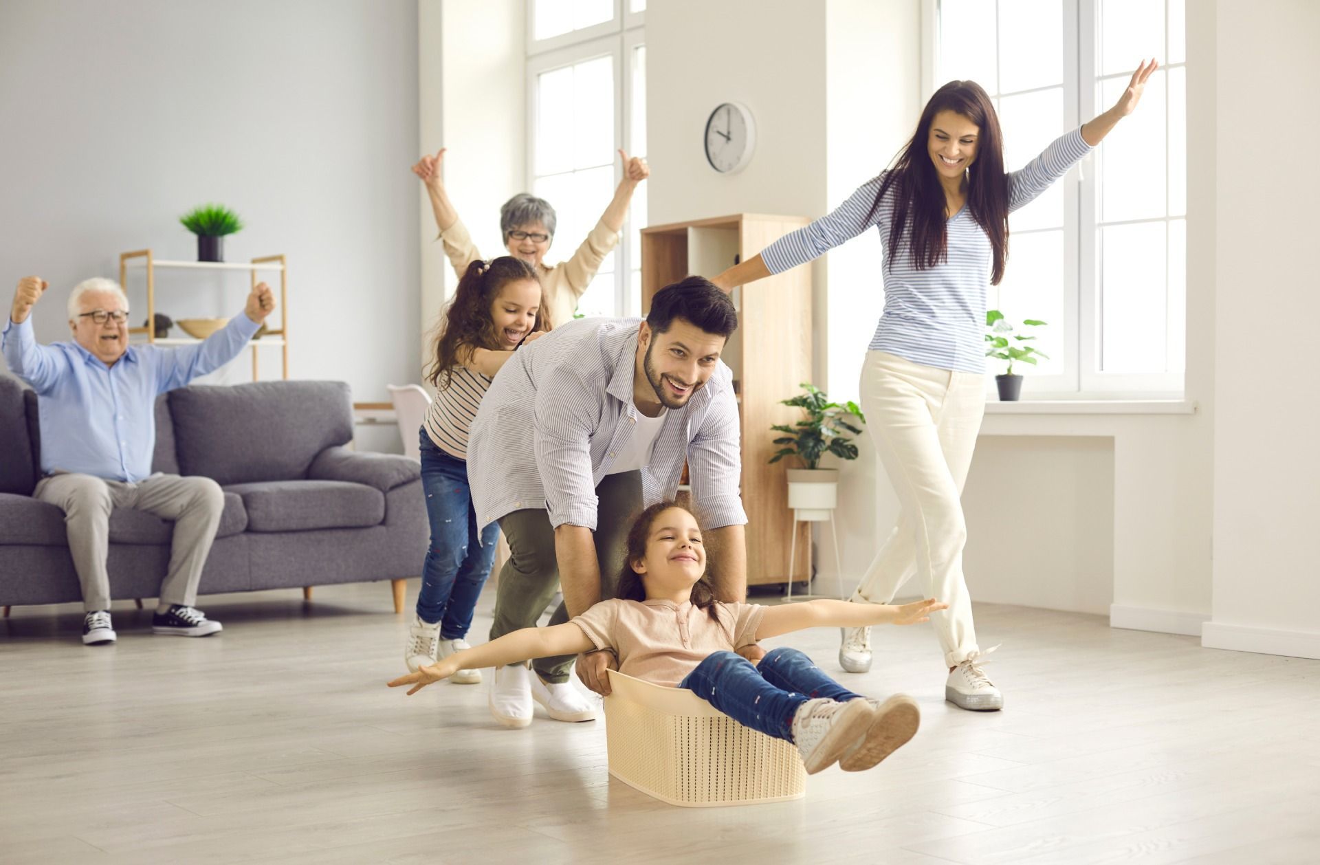 A family is playing with a cardboard airplane in a living room.