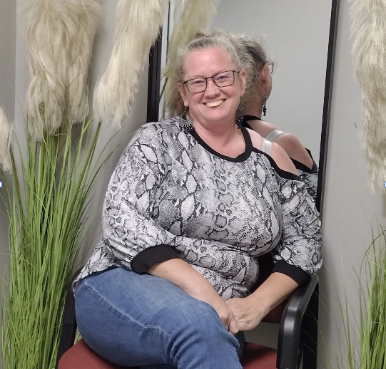 A woman with red hair is smiling and pointing at something
