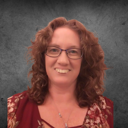A woman with red hair is smiling and pointing at something