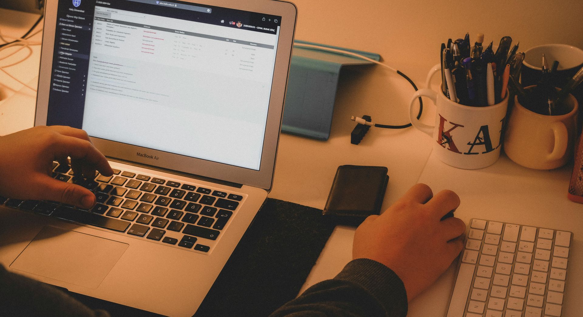 A person is typing on a laptop computer while sitting at a desk.