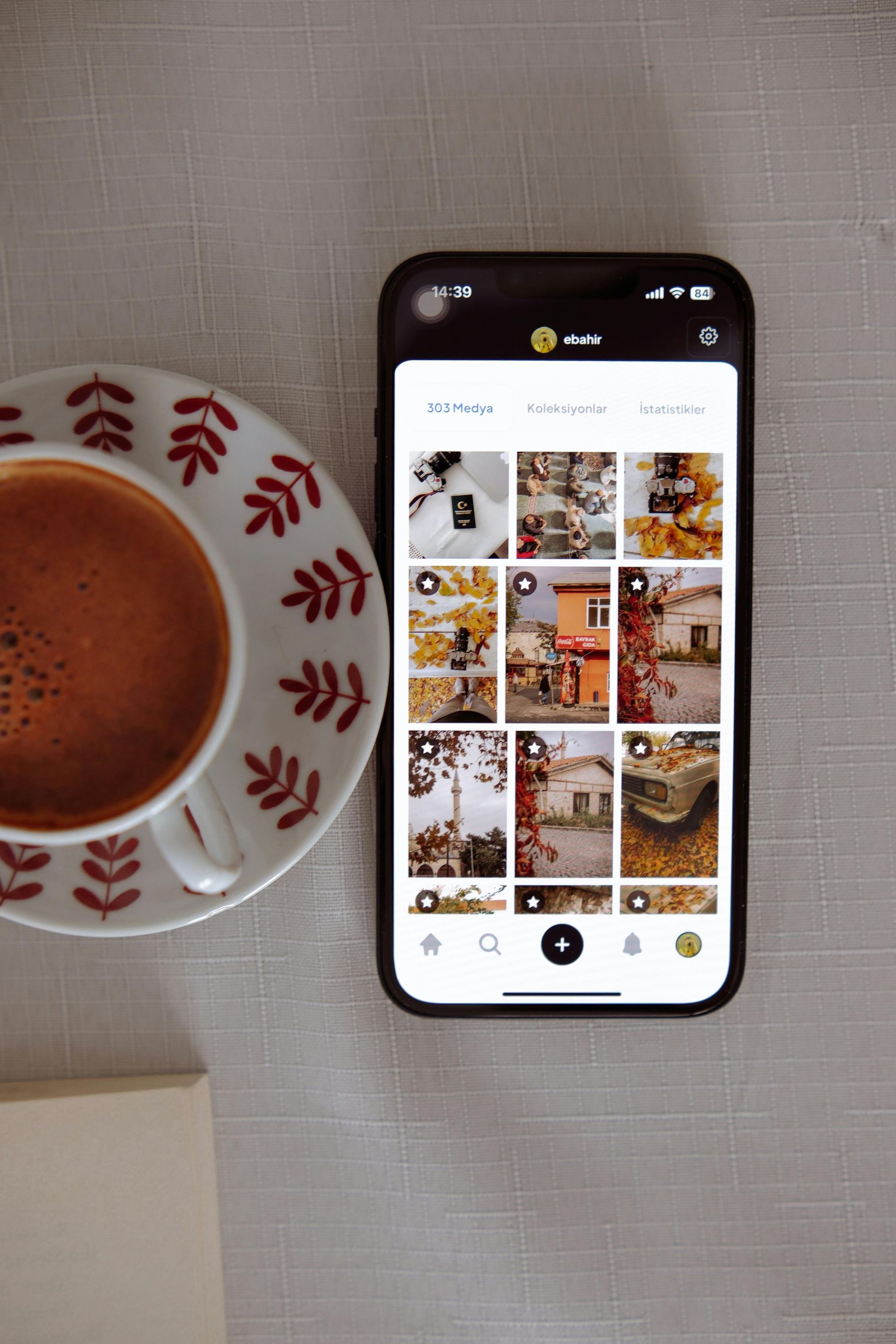 A cup of coffee and a cell phone on a table.