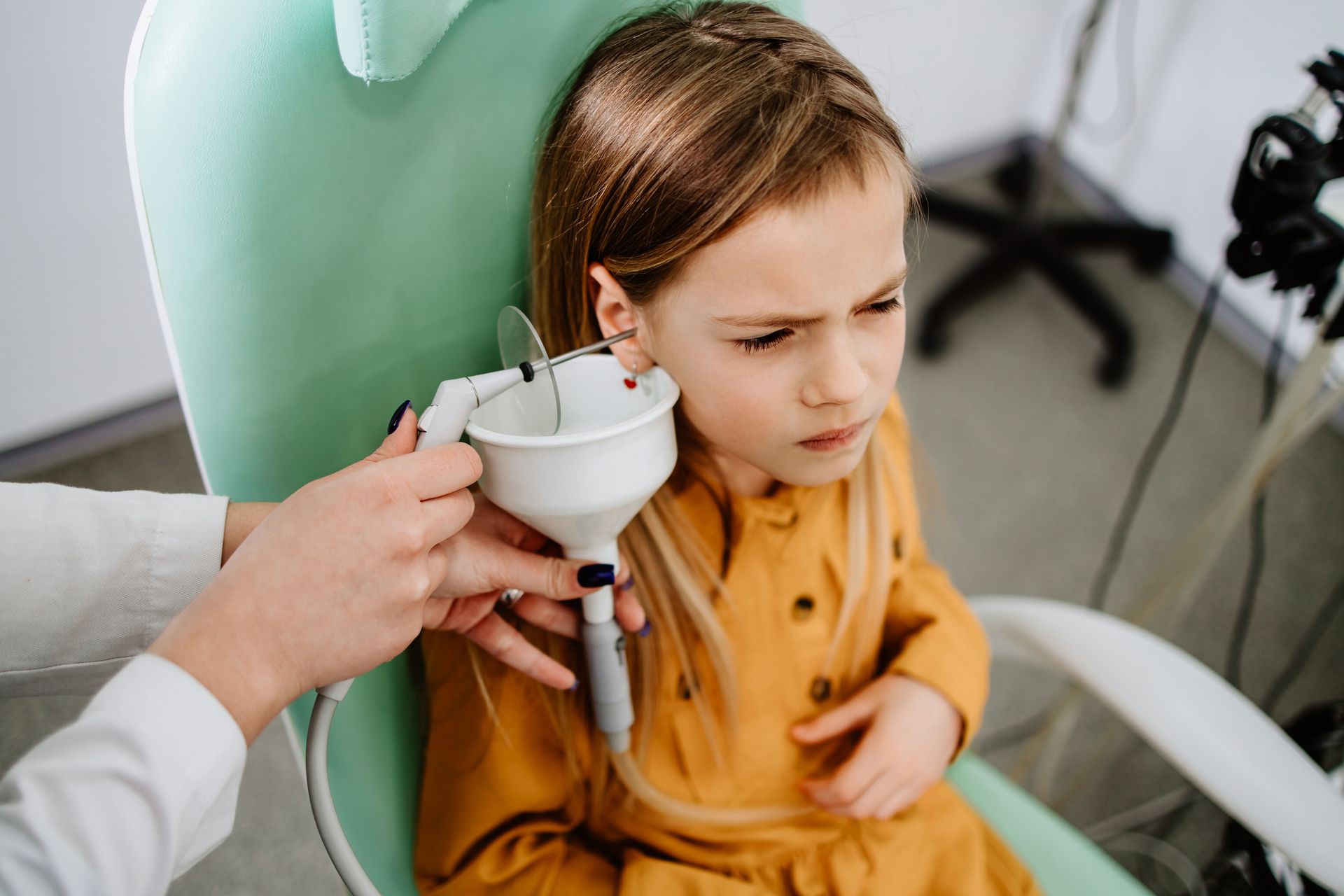 A little girl is getting her ears examined by an otolaryngologist.